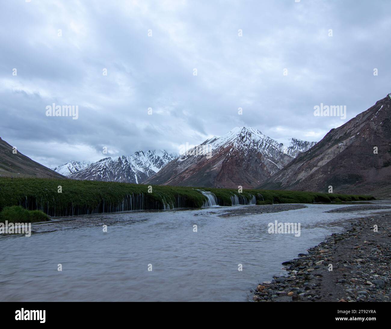 Long exposure landscape photo of snow capped peaks with water flowing like sand in foreground. Stock Photo