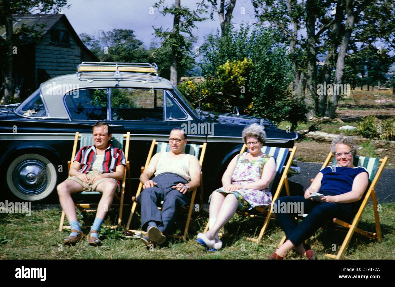 Two couples sitting in deckchairs next to a car on summer holiday, England, UK 1962 Stock Photo