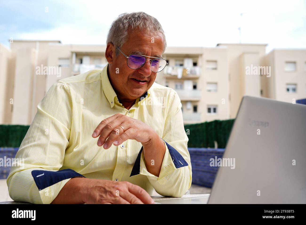 a businessman with a yellow suit working in the laptop outside Stock Photo