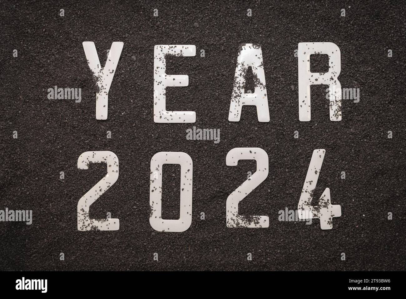 Happy New Year 2024: New Year 2024 concept on the black sand of a beach and the 2024 numbers seen from above. Stock Photo