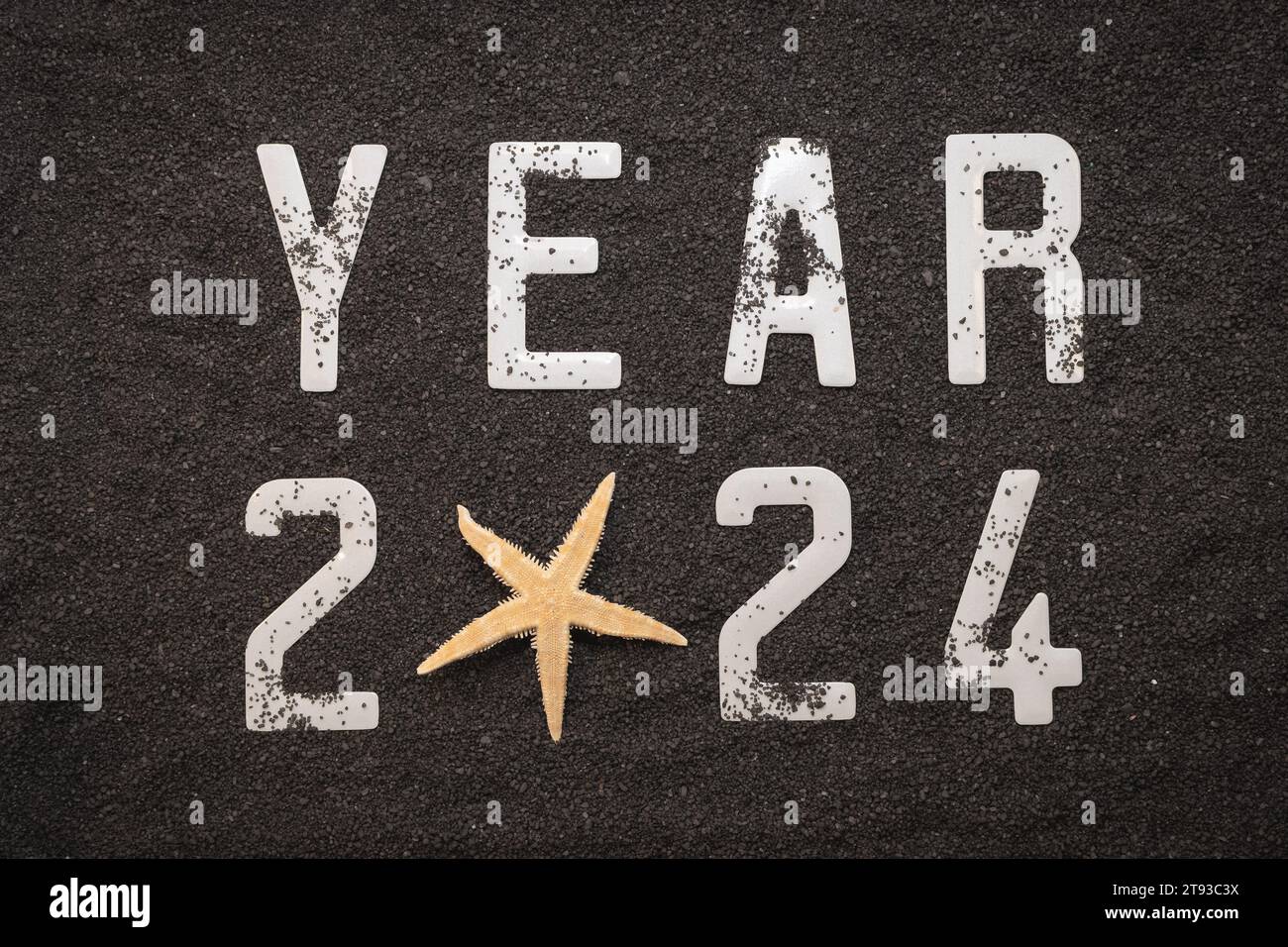 Happy New Year 2024: New Year 2024 concept on the black sand of a beach and the 2024 numbers seen from above. Stock Photo