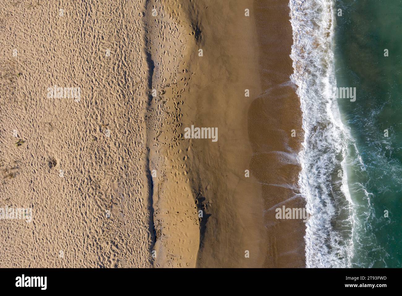 Aerial view of a remote sandy beach with foot steps and sea waves by drone Stock Photo