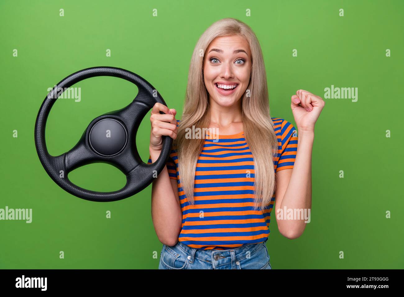 Portrait of young girl winner free automobile in national lottery raised fist up enjoying big jackpot isolated on green color background Stock Photo