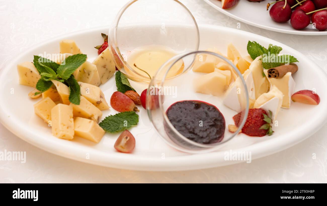 Sliced cheese on a plate with honey and sweet sauce, cheese products. Stock Photo