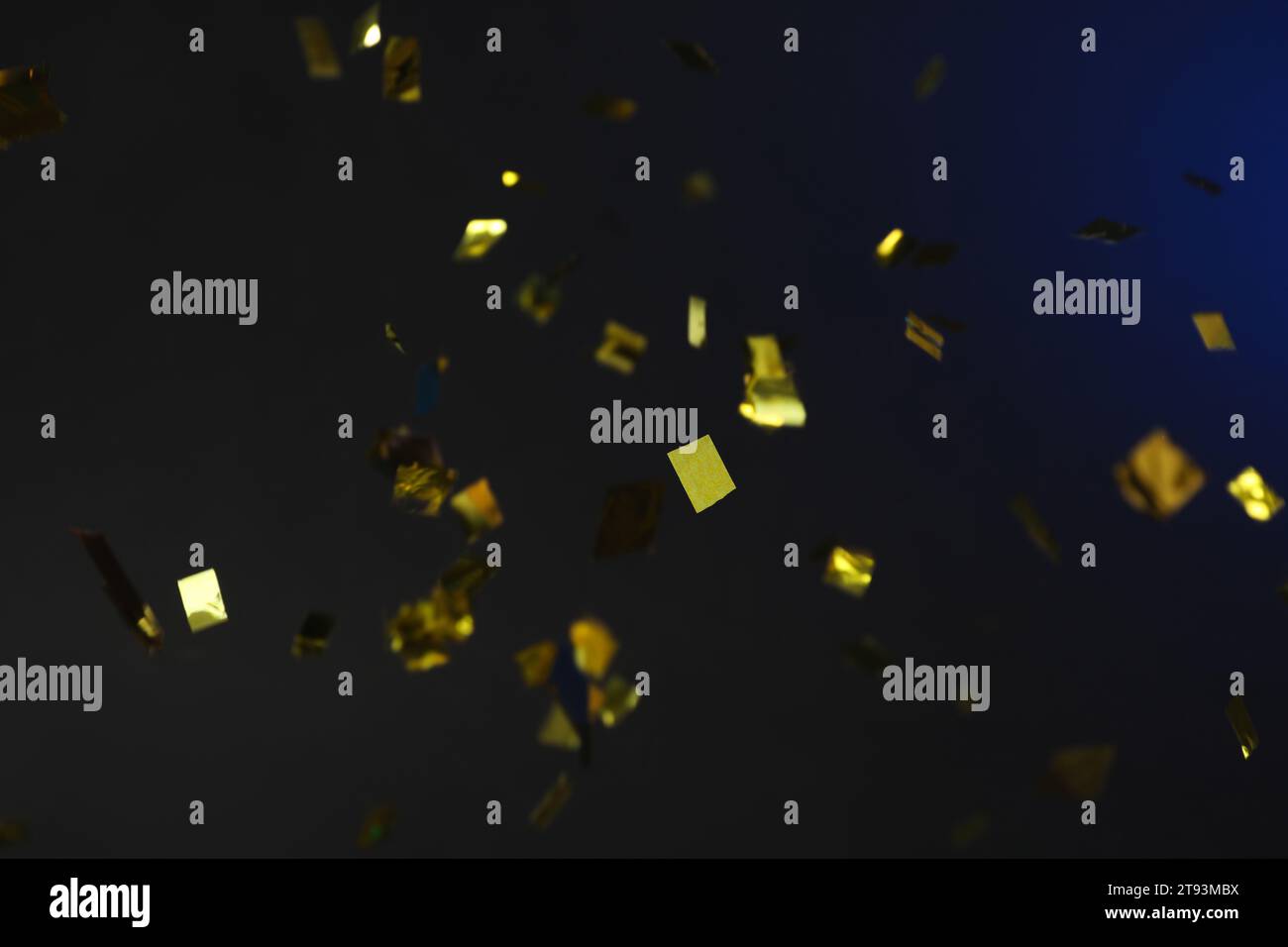 Shiny golden confetti falling down on dark blue background Stock Photo ...