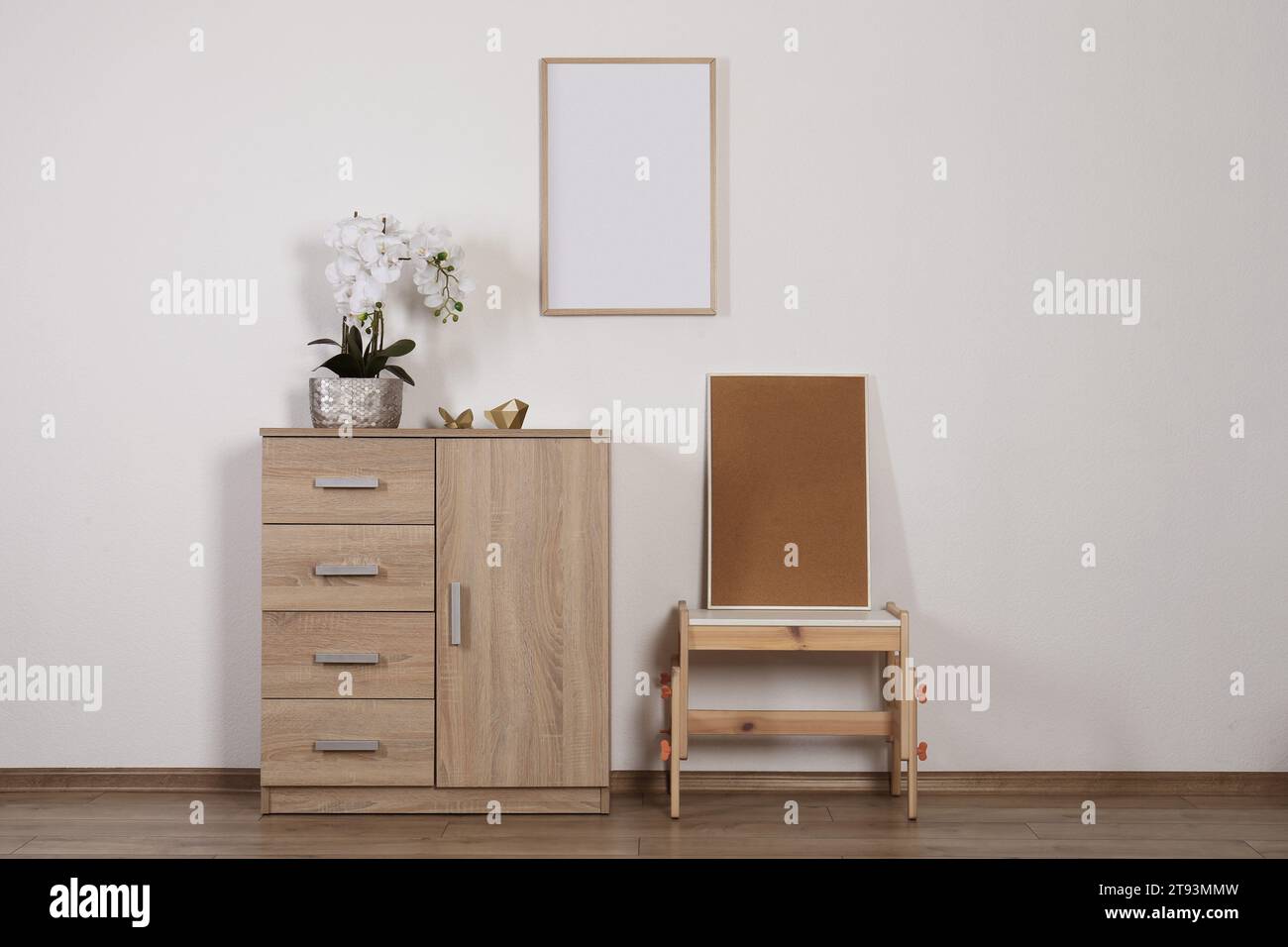 Chest of drawers, table, orchid and picture frames indoors. Interior design Stock Photo