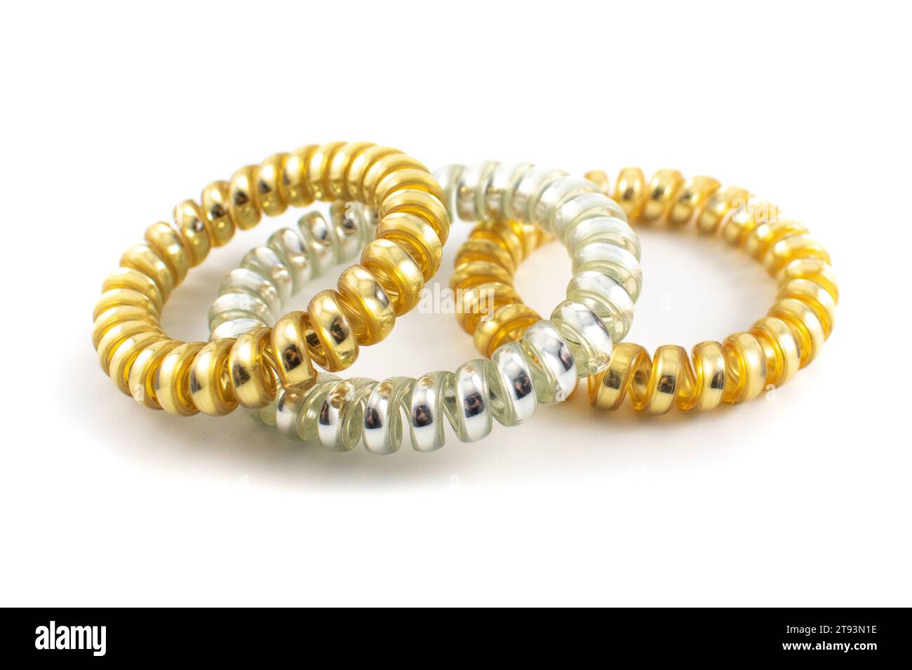 Close up photo of three metallic gold and silver plastic spiral hair ties Stock Photo