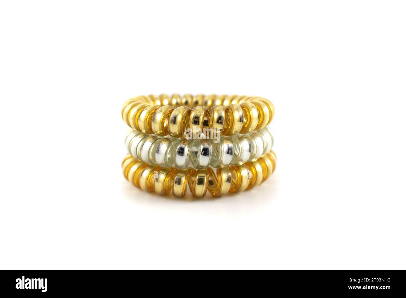 Close up photo of three metallic gold and silver plastic spiral hair ties Stock Photo