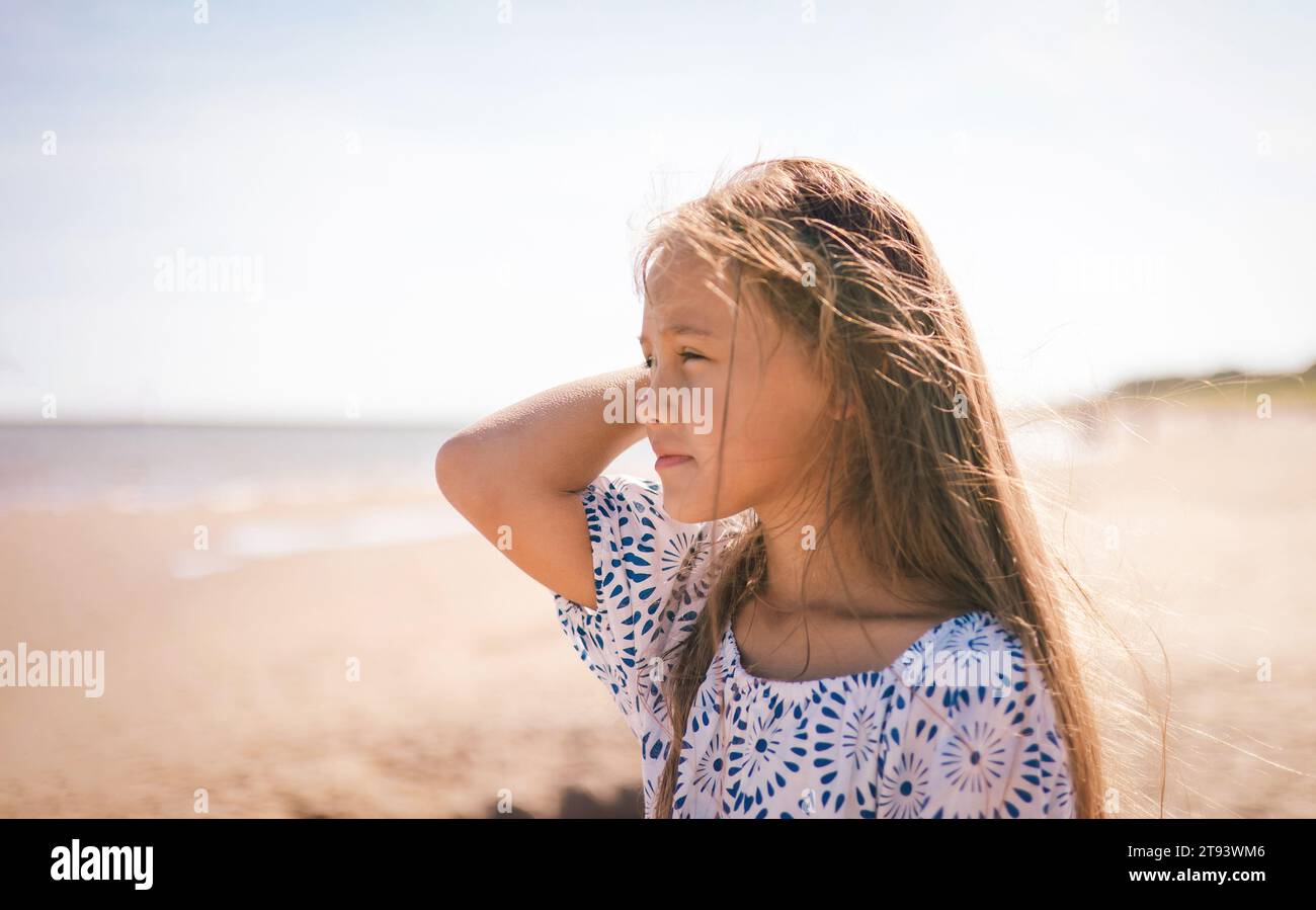Close-up of a young girl profile sunlight catching the strands of her tousled hair with a serene and thoughtful expression Stock Photo