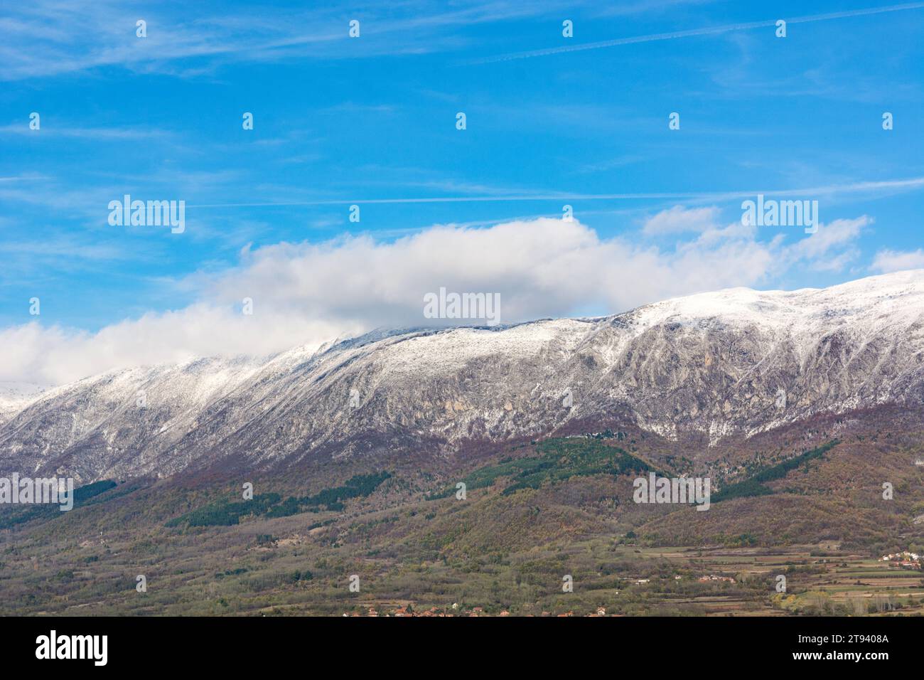 Snow covered peaks of a dry mountain, accompanied by white clouds in a national park. A beautiful blue sky dominates the chilly, sunny autumn day Stock Photo