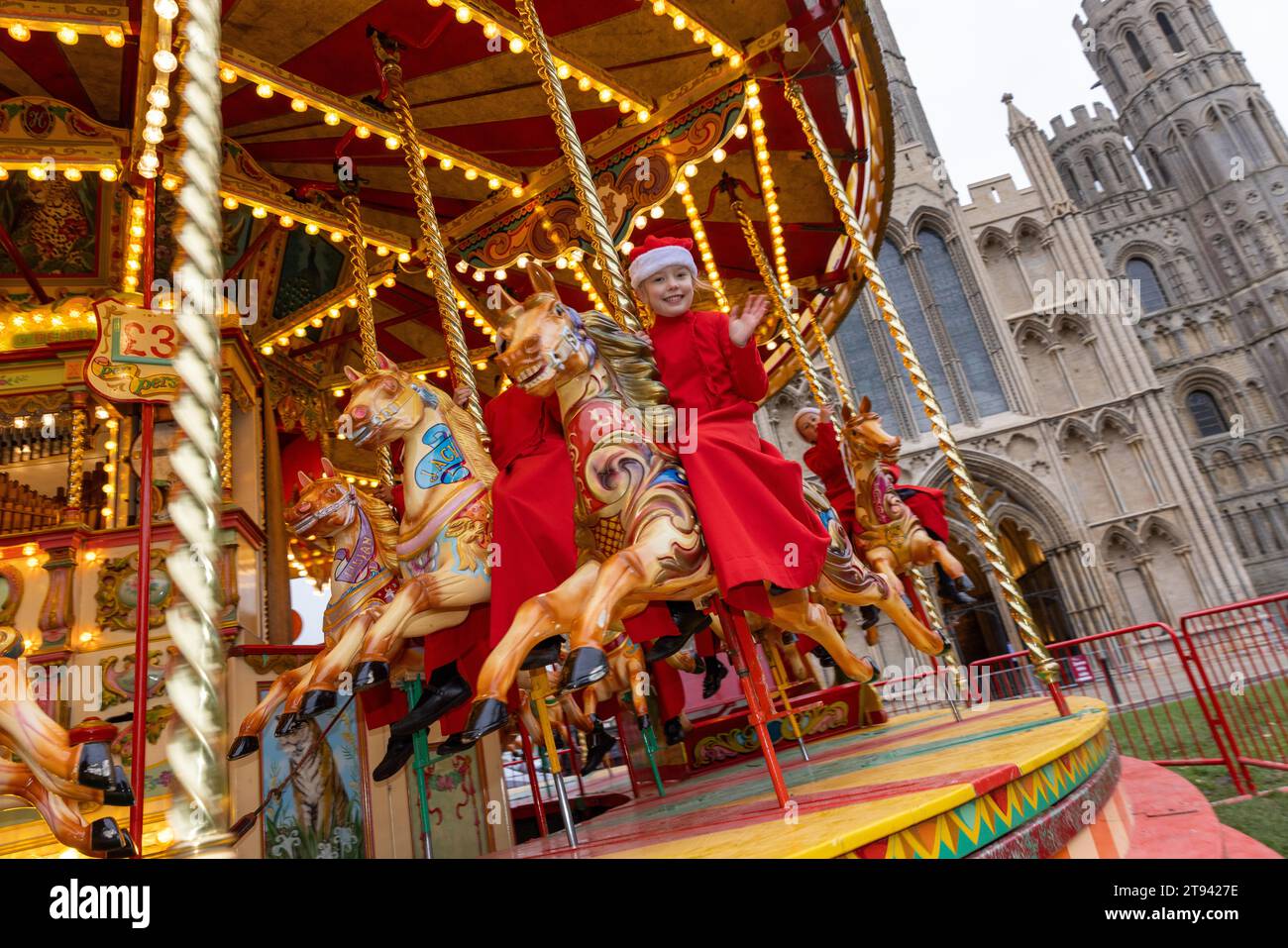 Choristers from Ely Cathedral  going for a spin on the  traditional carousel at the city’s Christmas market  after early morning choir practice . Stock Photo