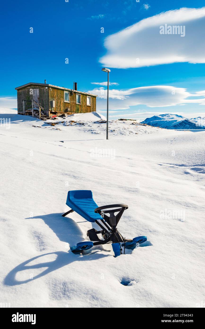 Snowracer in front of house in snowy Greenland under blue sky with ...
