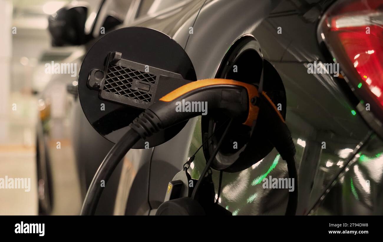 Electric Vehicle car or EV Car parking at charging station and plugged power cable supply. Charge power to EV or hybrid car battery. Green energy and Stock Photo