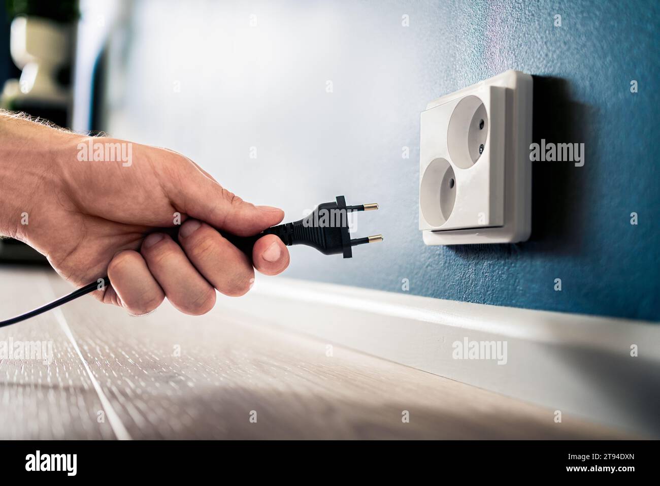 Socket, plug and electric power outlet. Man unplugging or holding cable wire cord in hand. Save energy. Electricity from home wall. Stock Photo
