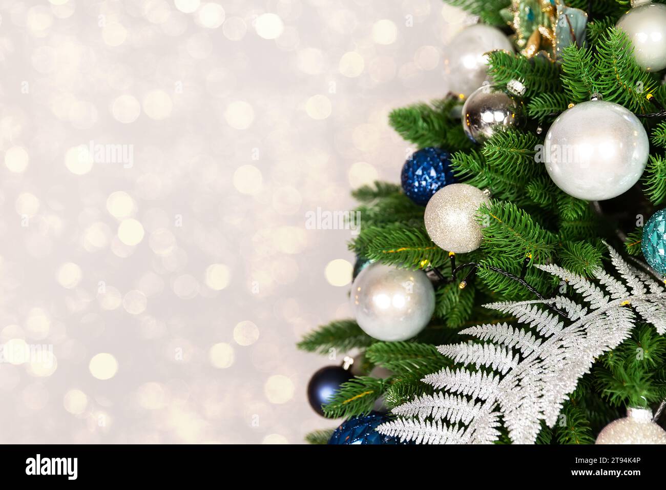 Holiday Christmas tree with ornaments and balls on golden background with bokeh lights. Merry Christmas and a happy New Year greeting card. Winter hol Stock Photo