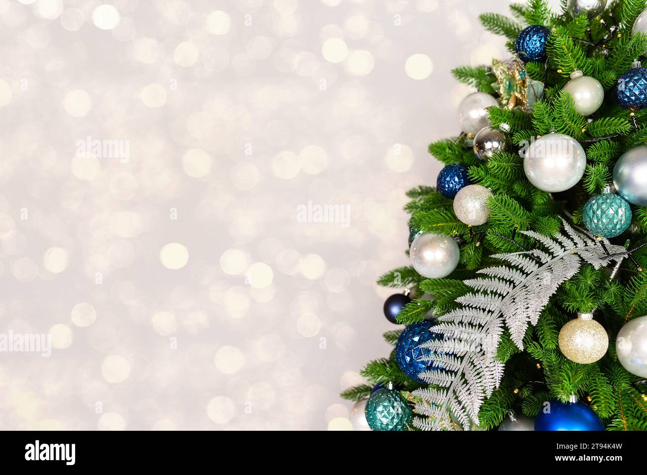 Holiday Christmas tree with ornaments and balls on silver background with golden bokeh lights. Merry Christmas and a happy New Year greeting card. Win Stock Photo
