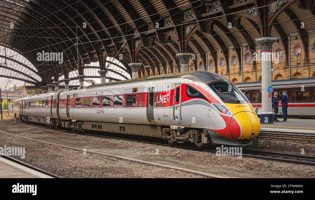 A modern train stands at a historic railway station platform under a