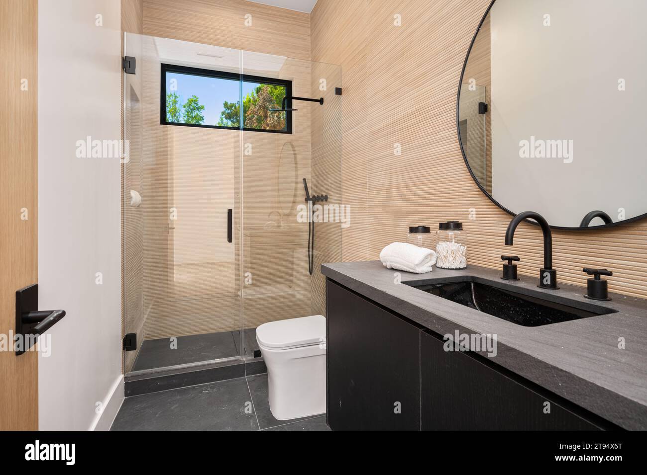 This bright and airy bathroom is ready to be used and enjoyed, featuring a modern shower and pristinely clean surfaces Stock Photo