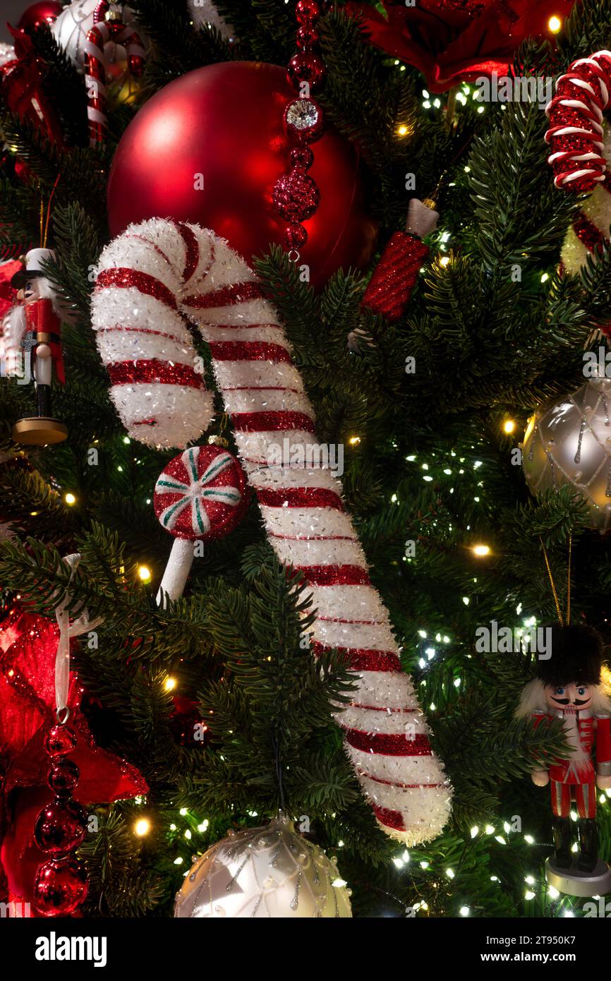 Glittery decorative red and white candy cane decoration and bauble ornaments on a green Christmas tree for season greetings concept Stock Photo