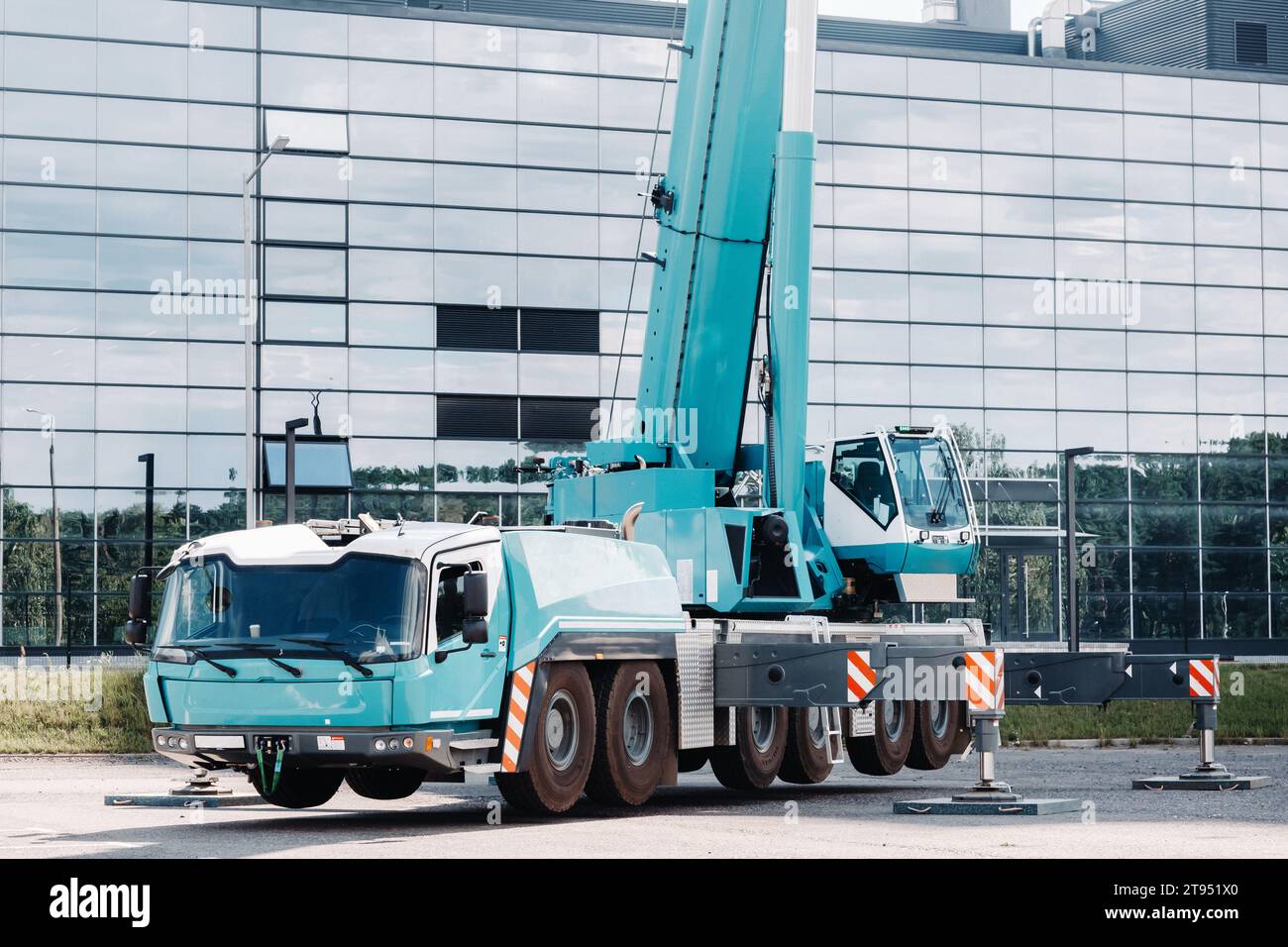 A large blue truck crane stands ready to operate on hydraulic supports
