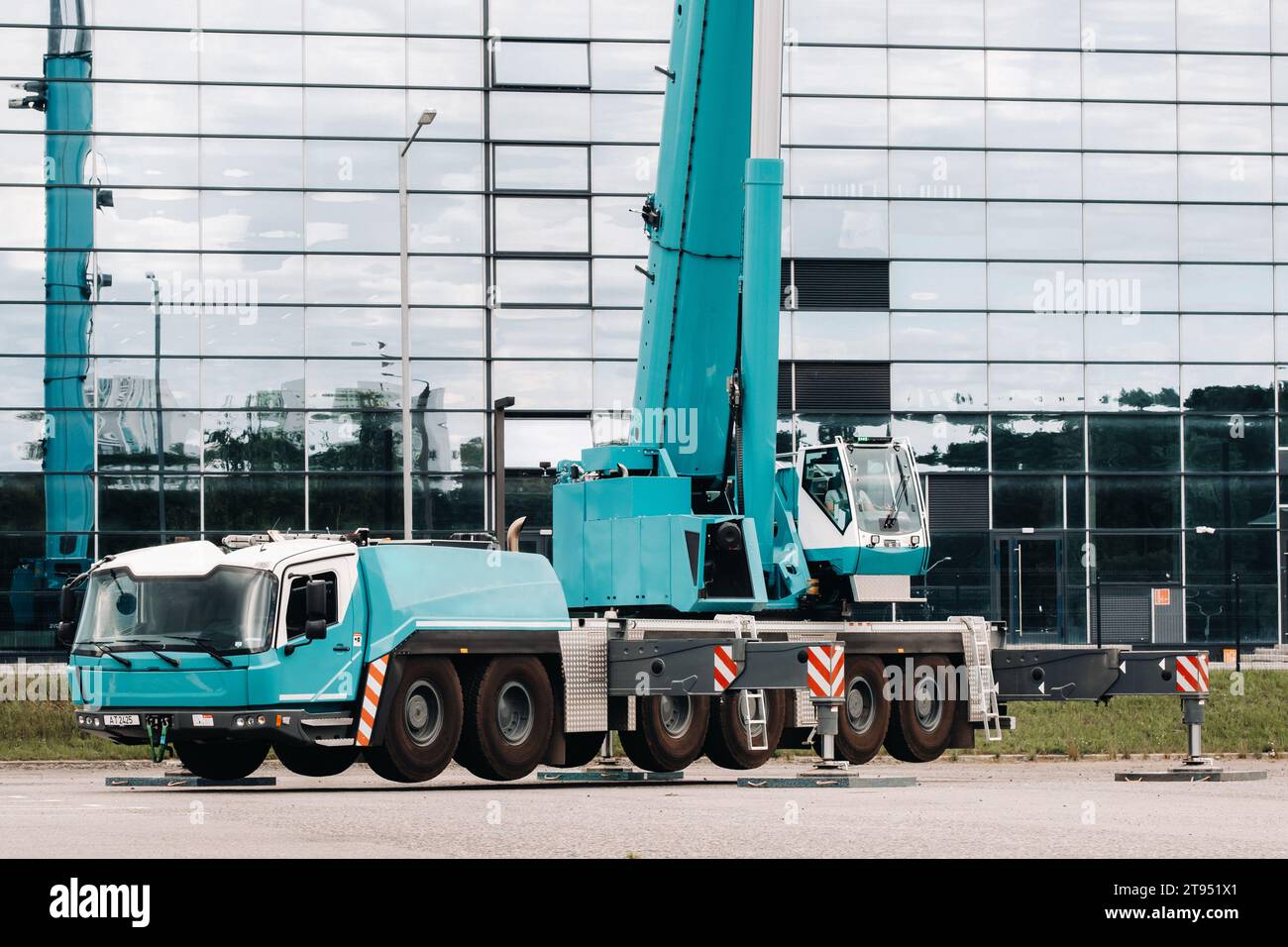 A large blue truck crane stands ready to operate on hydraulic supports