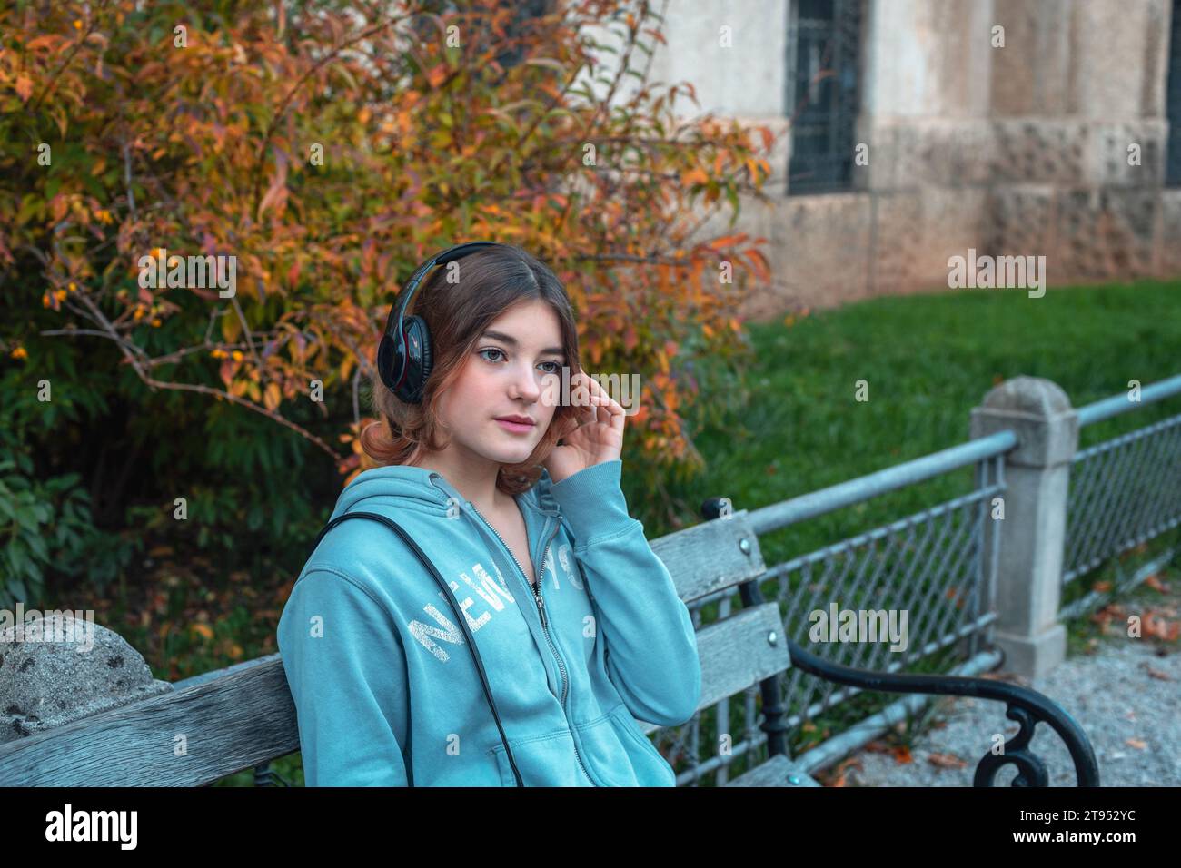 Beautiful young girl in headphones sitting on a bench Stock Photo - Alamy