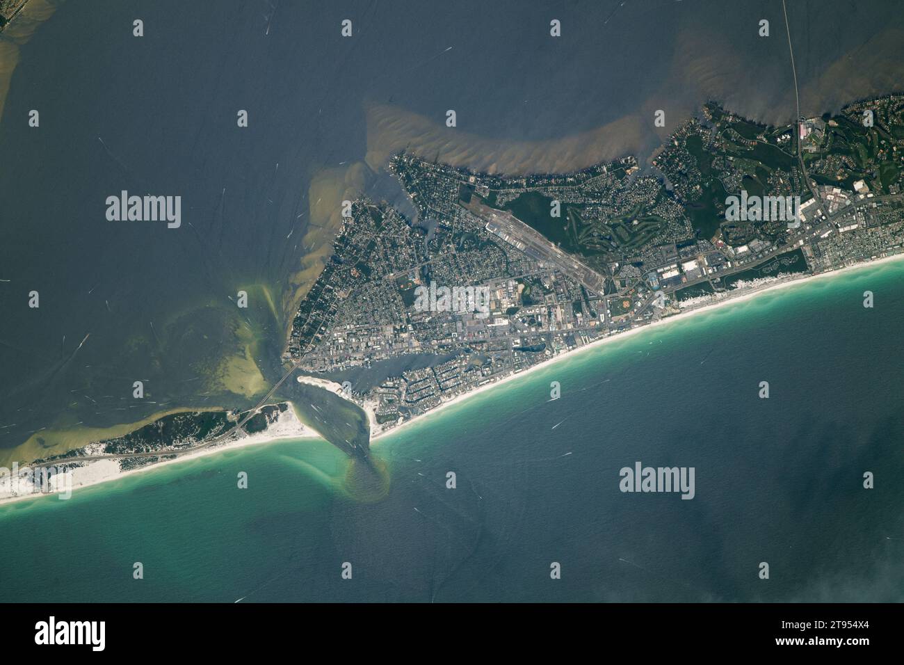 July 30, 2023 - Florida, USA - An astronaut aboard the International Space Station took this photograph of Destin, Florida, a beach city situated on the Gulf of Mexico coastline. Destin is part of Florida's Emerald Coast, an area which spans about 100 miles of the Florida Panhandle. The beaches in this area are known for their 'sugary white' sand and green-toned waters. The white sand is comprised primarily of quartz grains that were transported from the southern Appalachian Mountains by the Apalachicola River system. Sunlight interacting with algae in the water produces the emerald color. (Cr Stock Photo