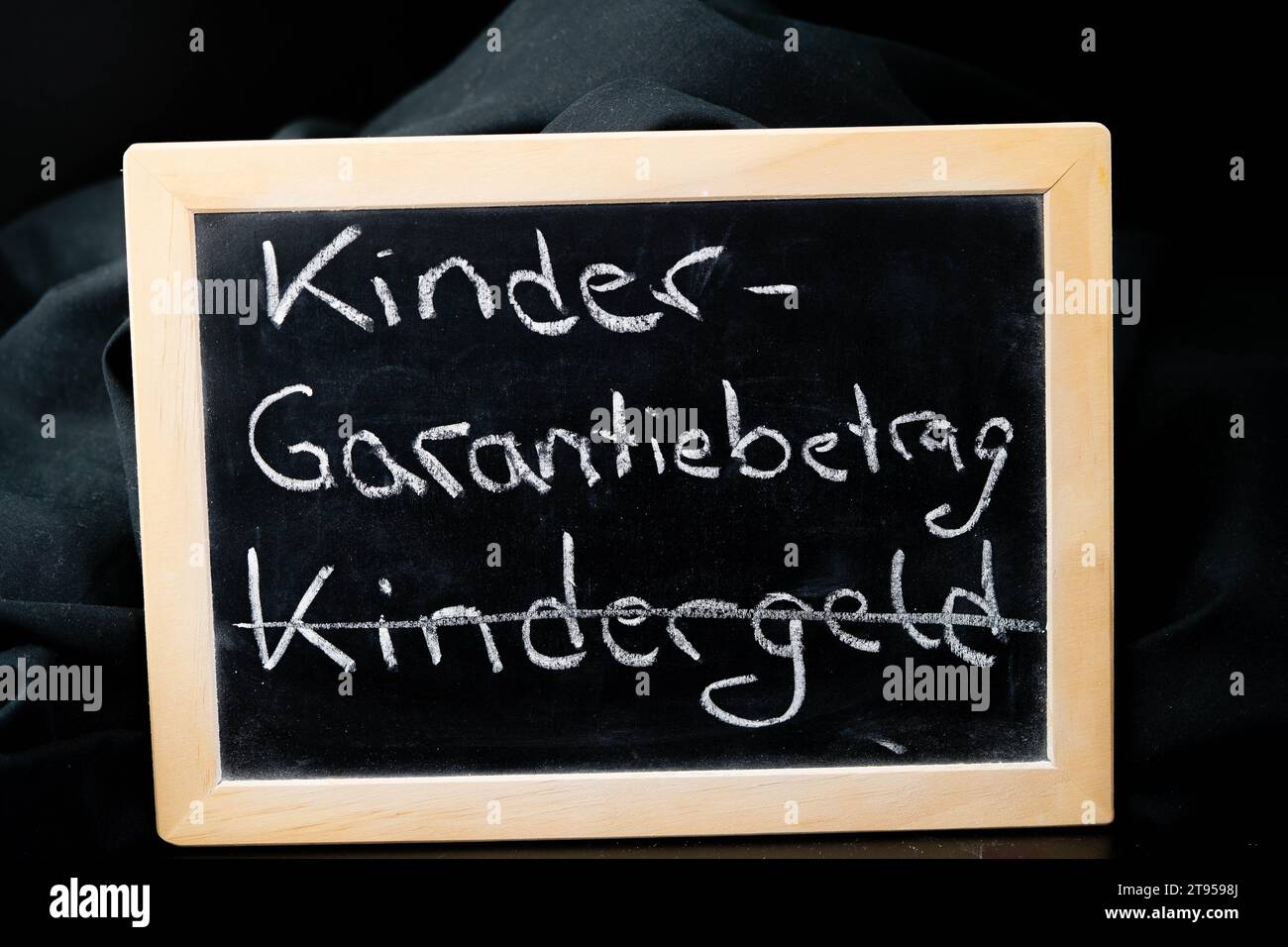 Chalkboard with the words Child Guarantee Amount, Kindergarantiebetrag, crossed out: Child benefit, Kindergeld Stock Photo