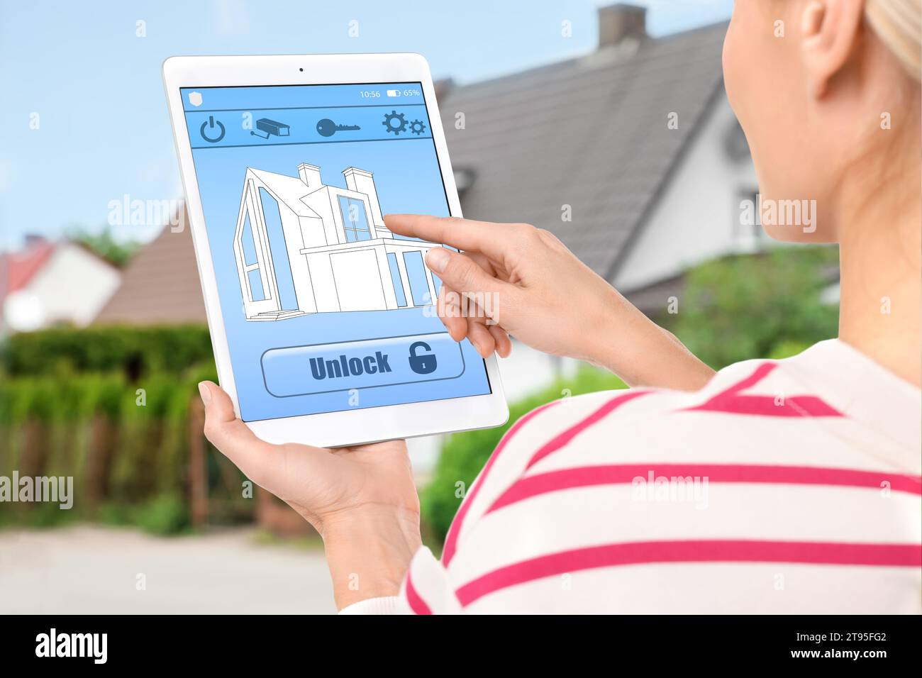 Woman using home security system application on tablet outdoors, closeup Stock Photo