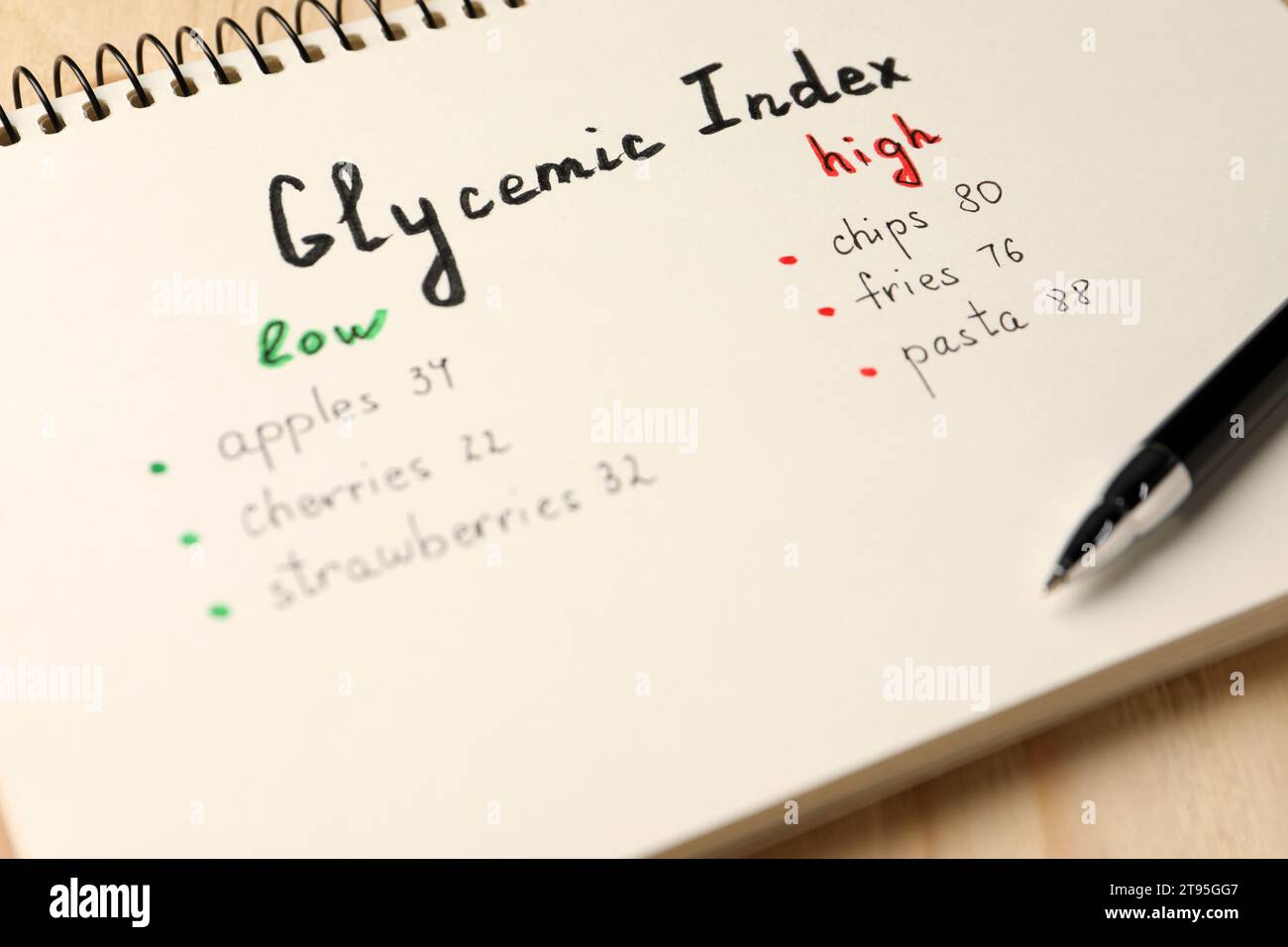 List with products of low and high glycemic index in notebook and pen on table, closeup Stock Photo