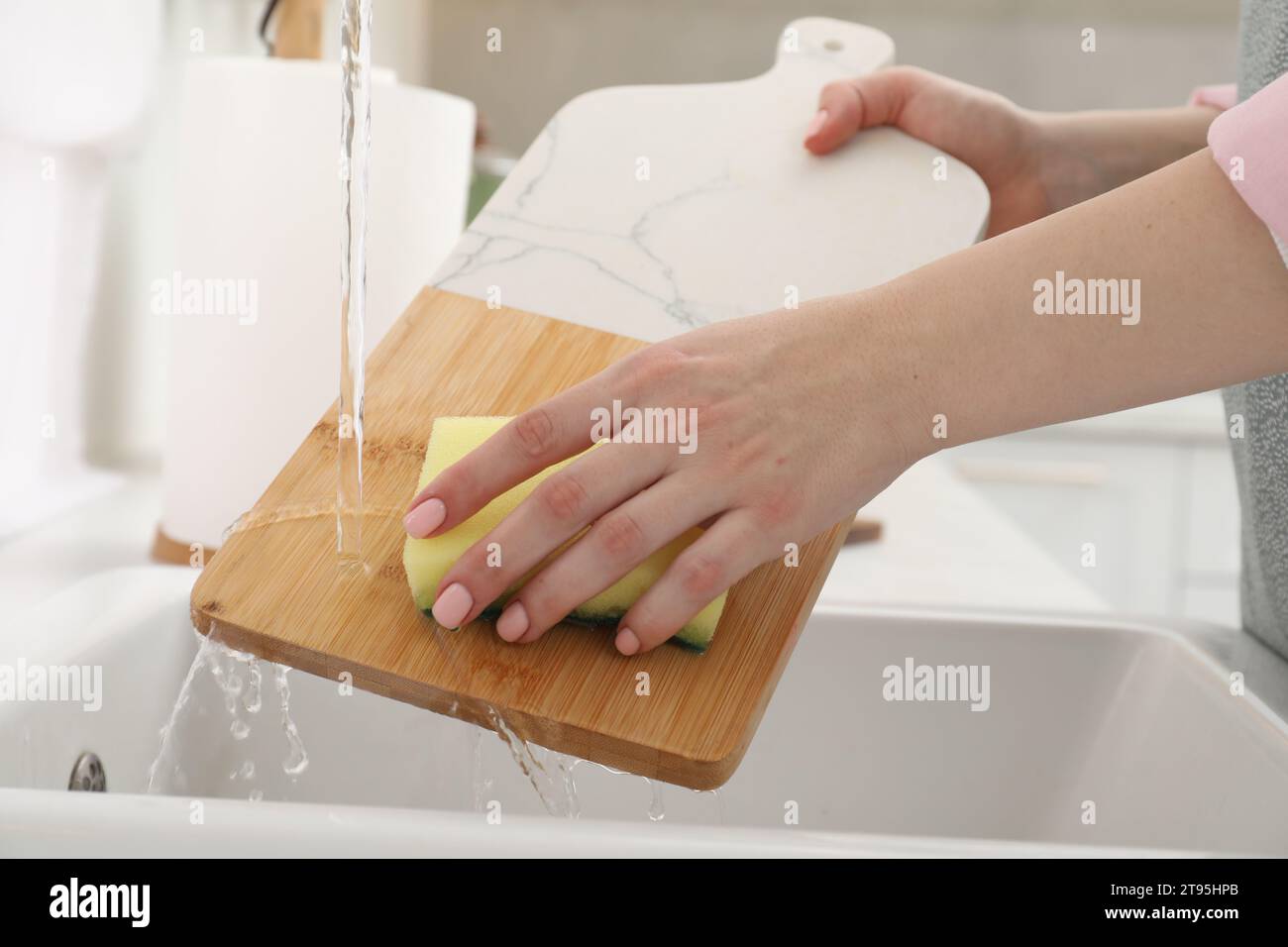 Woman washing cutting board at sink in kitchen, closeup Stock Photo