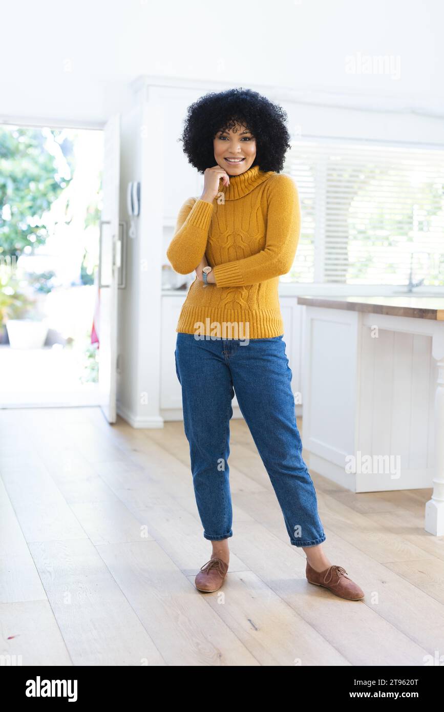 Happy african american woman standing with hand on face at home, copy space Stock Photo