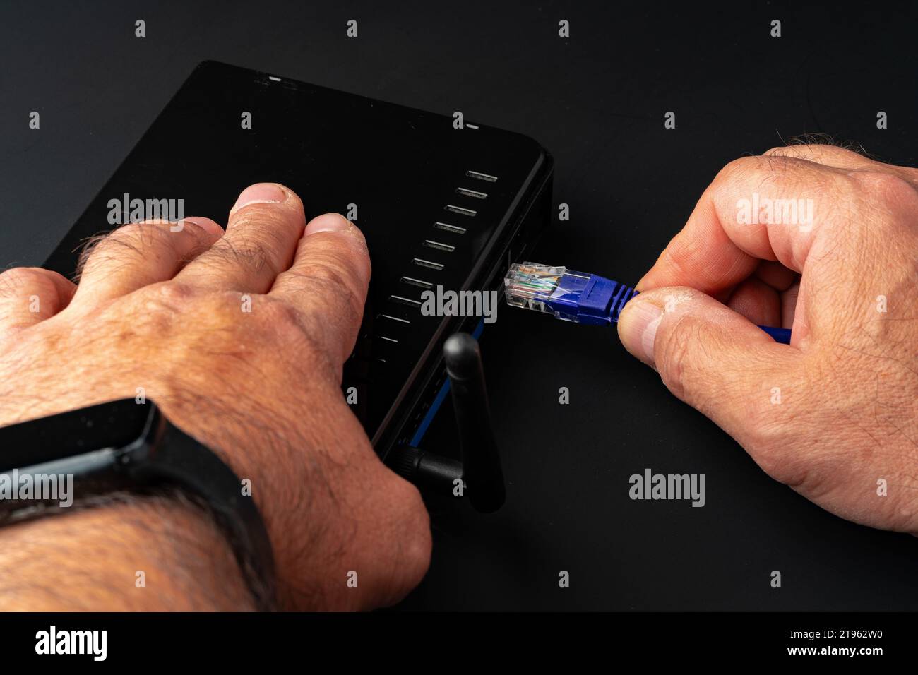 Man's hand plugging internet cable into wifi router Stock Photo