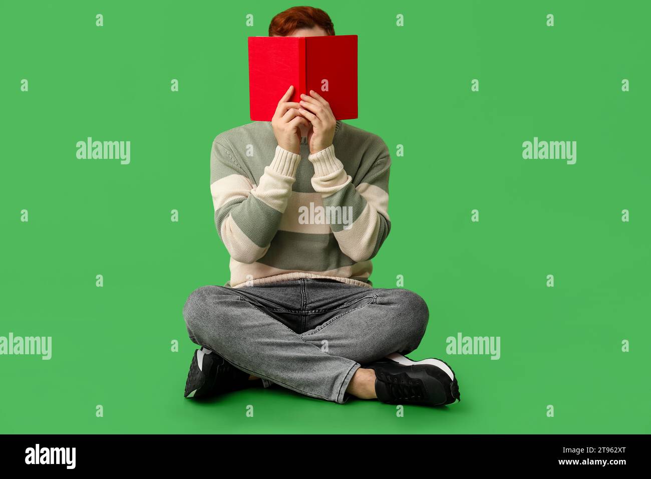 Young man covering his face with book on green background Stock Photo ...