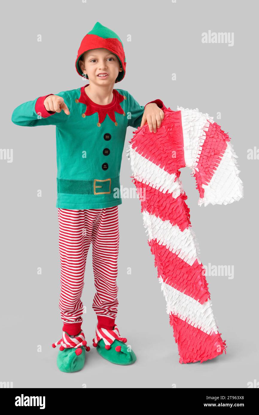 Cute little boy in elf's costume with candy cane pinata pointing at