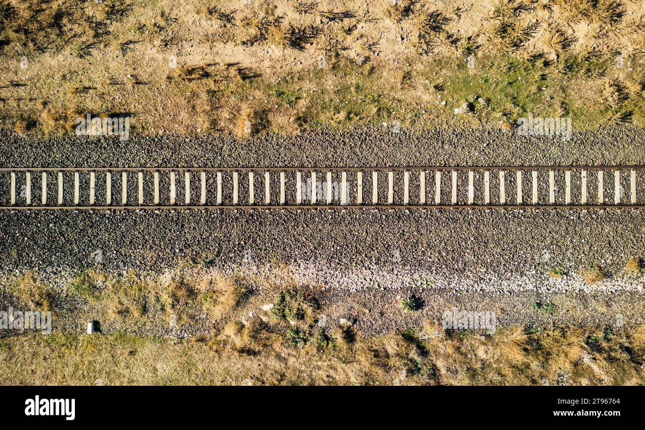 Top view of the train track passing through the arid land, taken with a drone Stock Photo