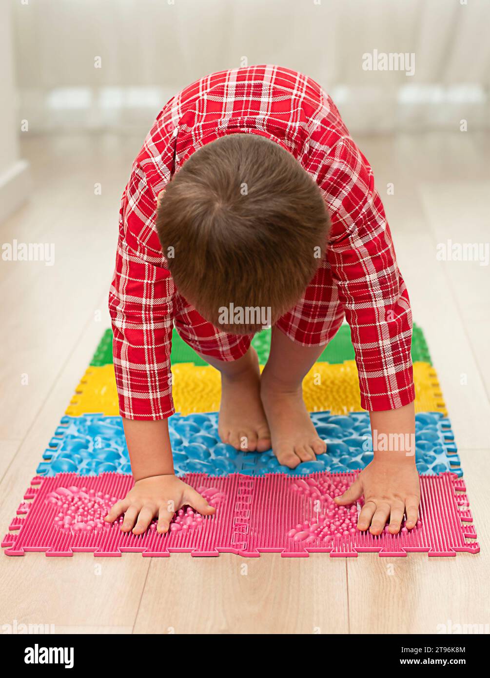 https://c8.alamy.com/comp/2T96K8M/sport-and-health-concept-a-little-boy-4-years-old-in-red-checkered-pajamas-is-working-out-on-a-multi-colored-massage-orthopedic-mat-with-spikes-in-a-2T96K8M.jpg