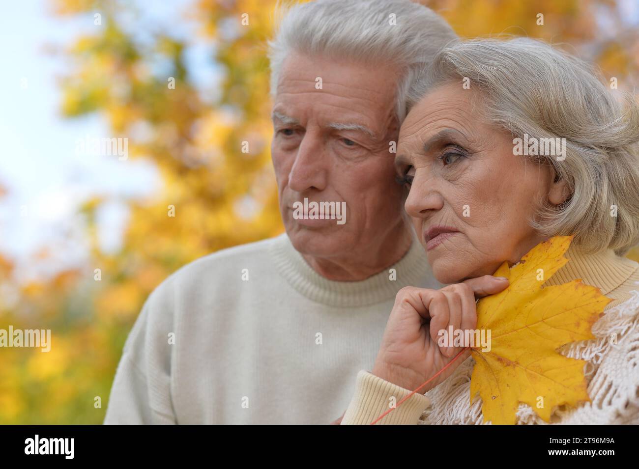 Portrait of sad senior couple in autumn park Stock Photo