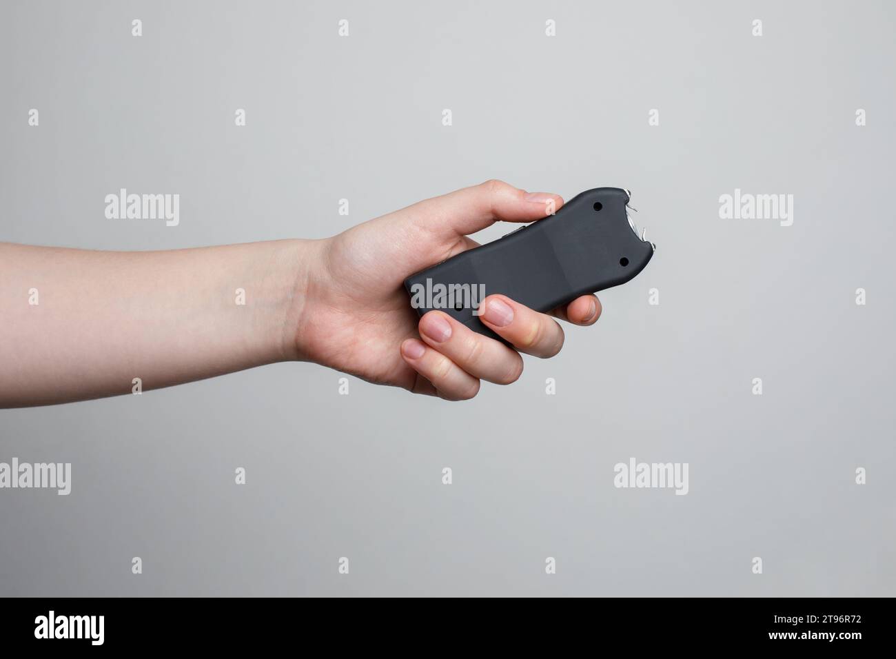Taser in human's hand close-up on a gray background Stock Photo