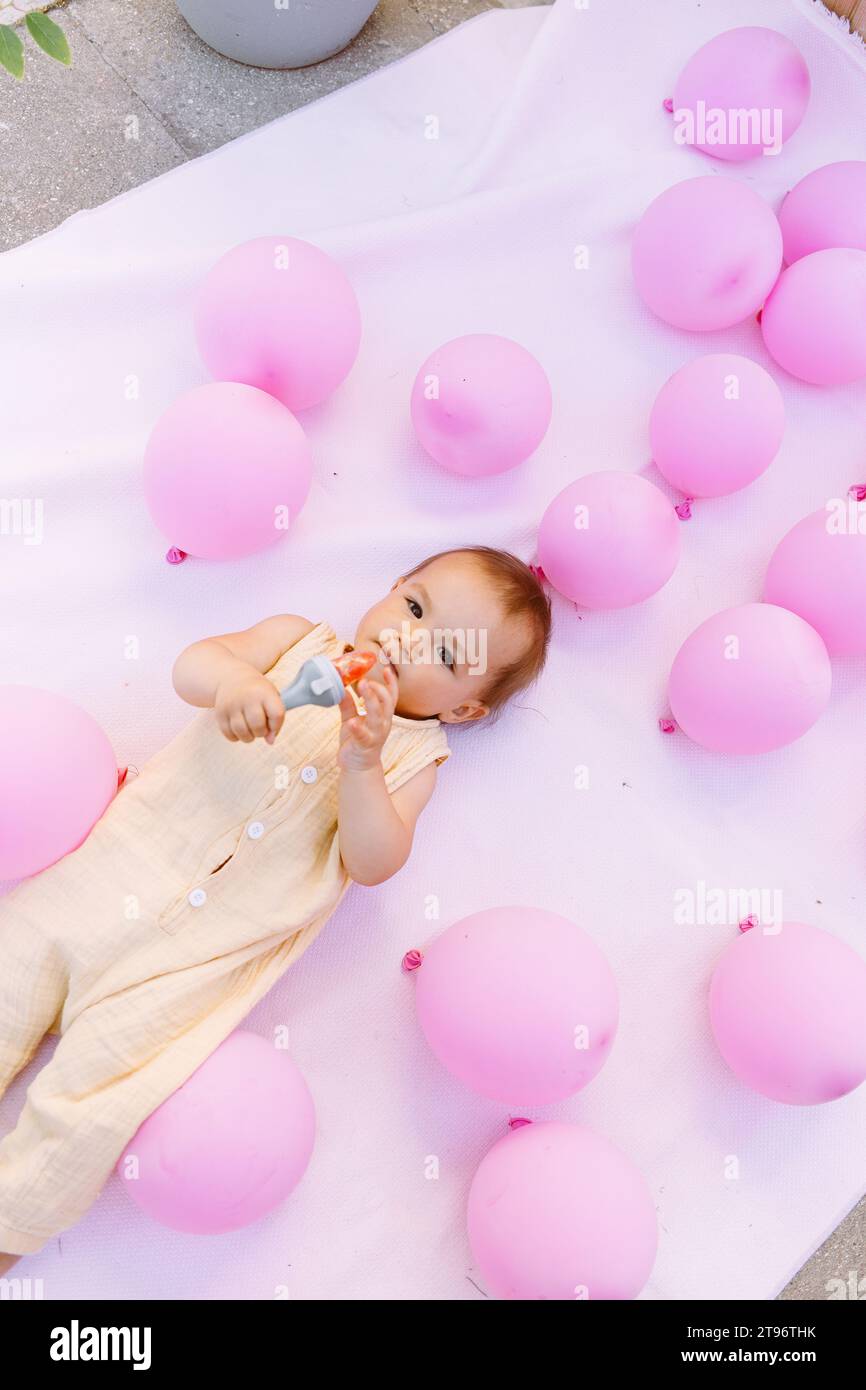 Balloon Rattle High angle of adorable toddler with rattle lying on cloth on floor near ...