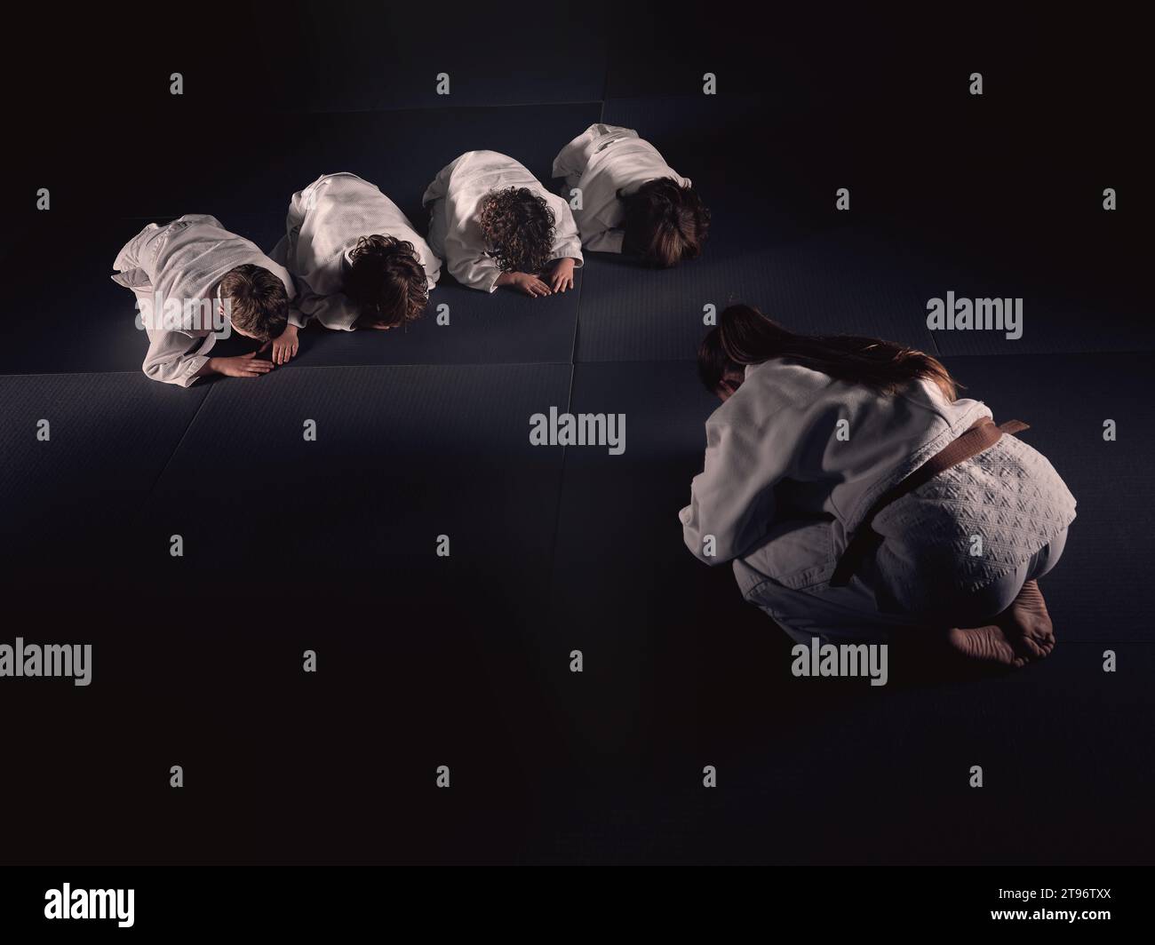 Anonymous Krav Maga female trainer and kids in white clothes bowing on