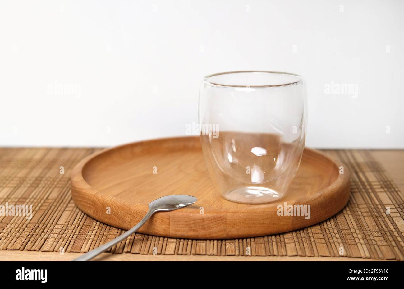 Empty double wall cup for tea or coffee on a table in a restaurant, cafe. Transparent cylindrical crystal mug over wooden table in the bar. Space for Stock Photo