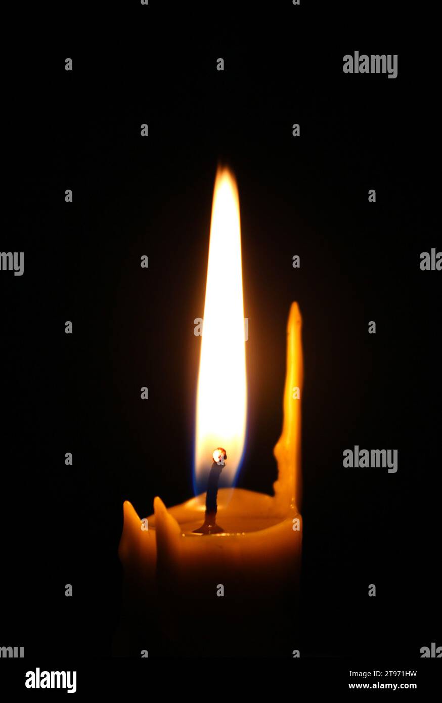 Single candle with wax streaks and an even flame in total darkness