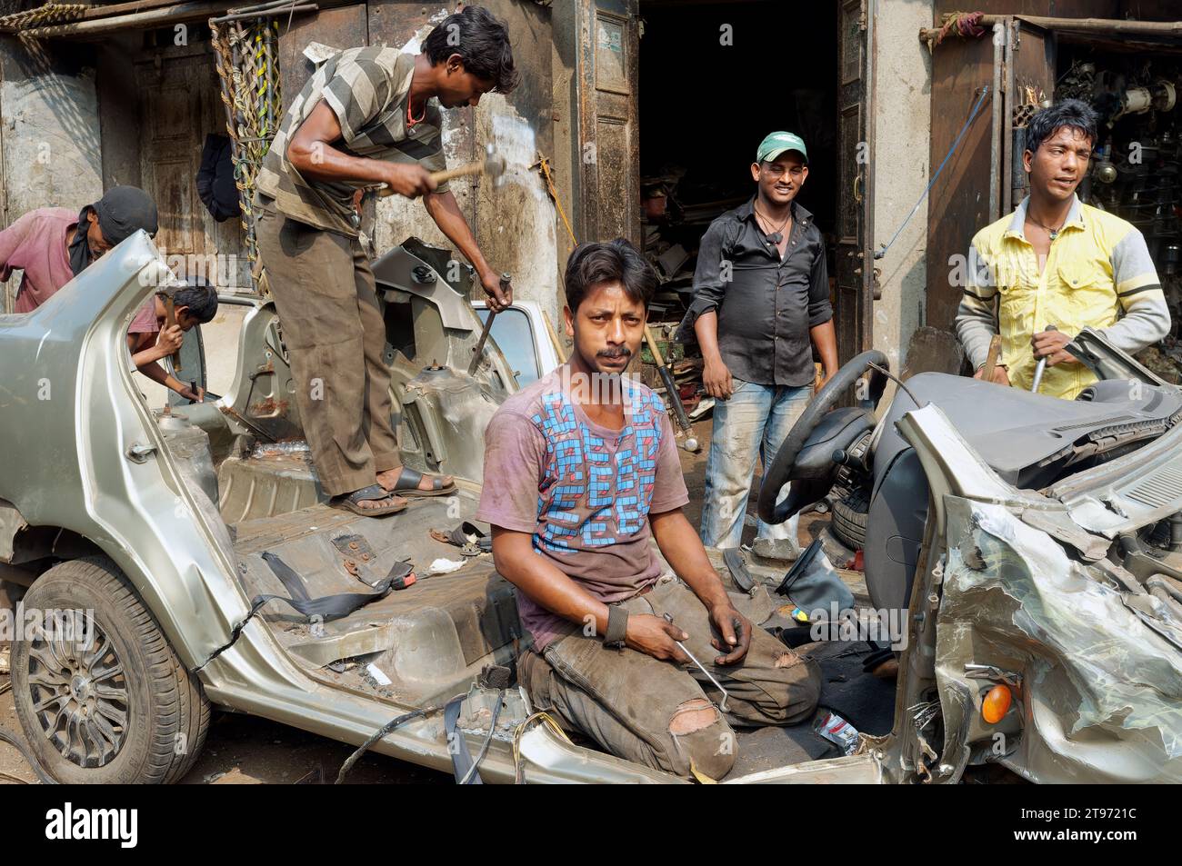 At Chor Bazar or Thieves' Market in Mumbai, India, a group of young men dismantle a car to sell for scrap and spare parts Stock Photo