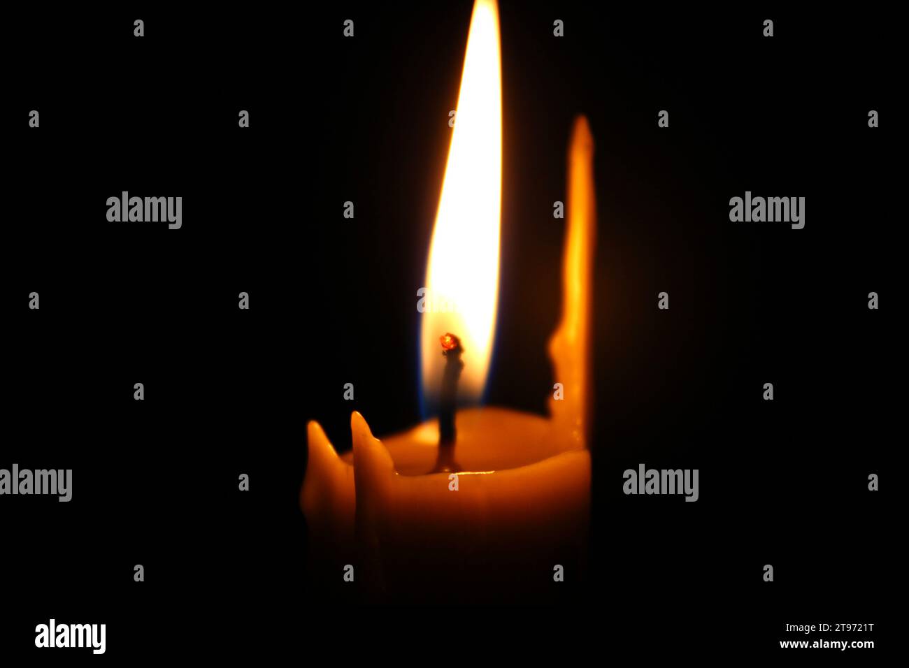 Fire around the wick of a melted wax candle closeup. Concept for smartphone wallpaper or vertical mourning card Stock Photo