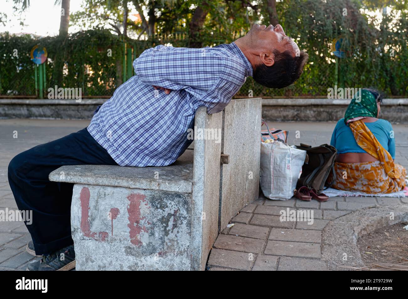 An Indian man sits on an cement bench at Marine Drive