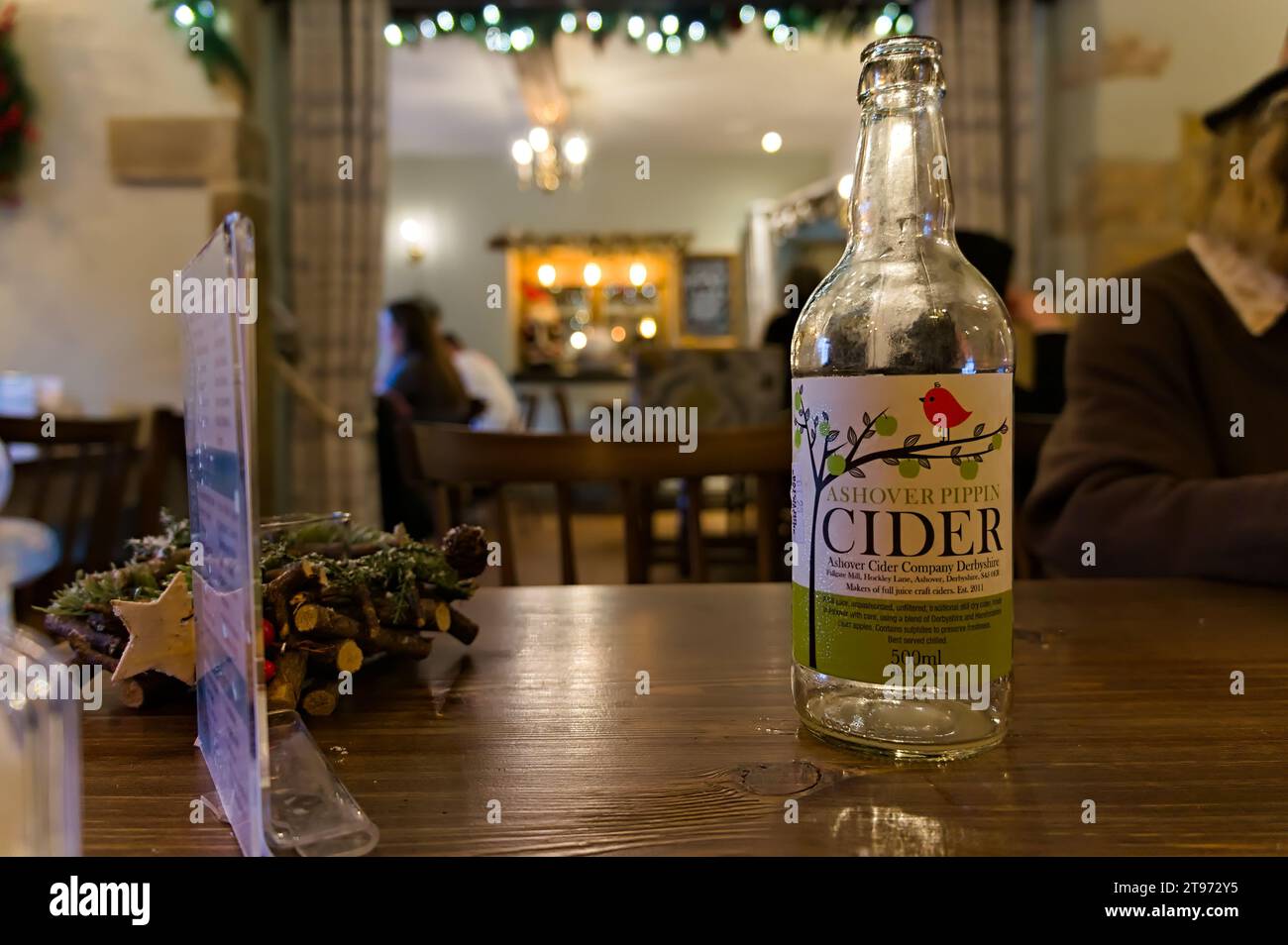 A bottle of Ashover cider on a tabletop with a restaurant soft focused in the background Stock Photo