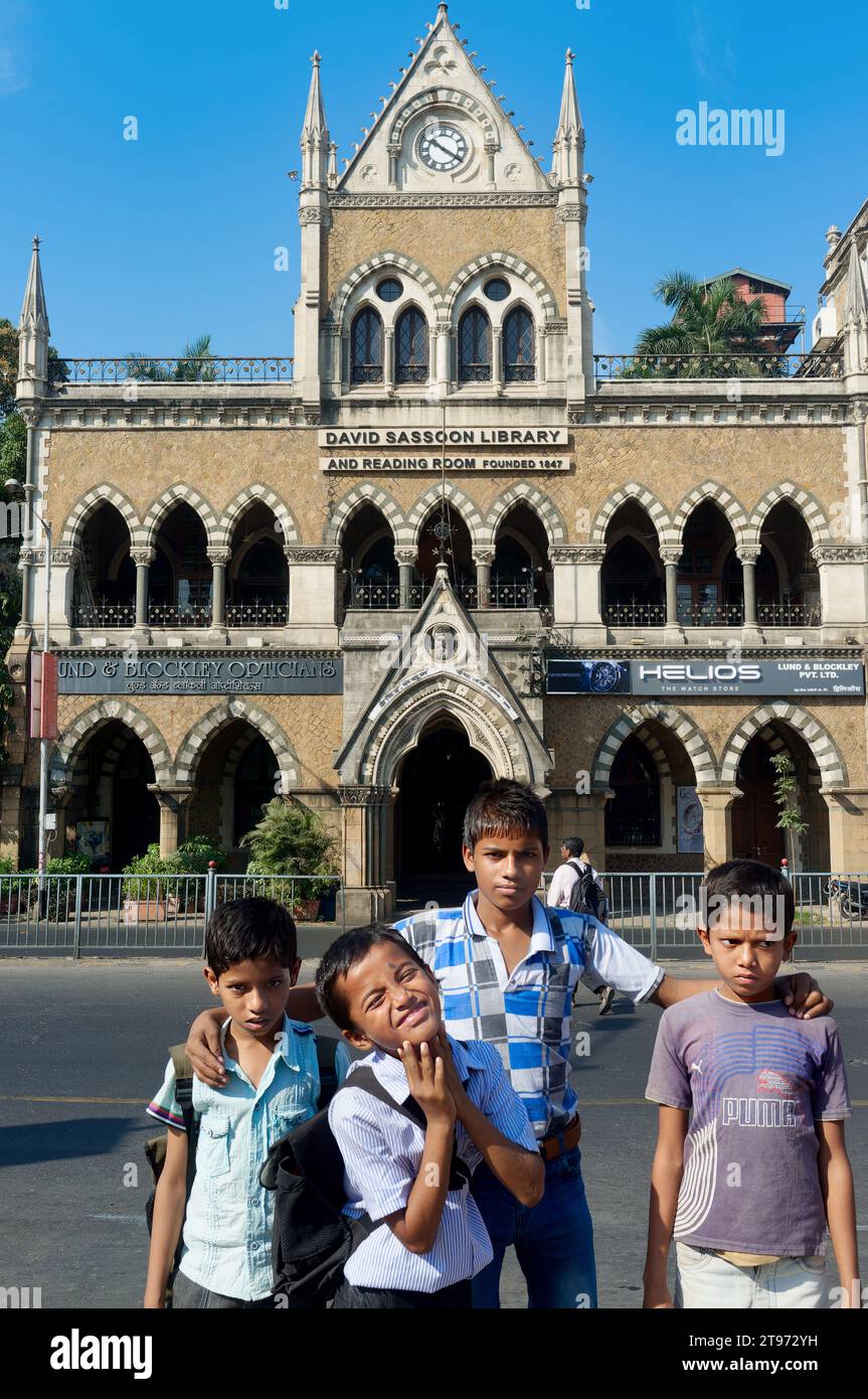 Young Indian boys pose in front of heritage building David Sassoon Library built in 1867-70; at Kala Ghoda, Fort, Mumbai, India Stock Photo