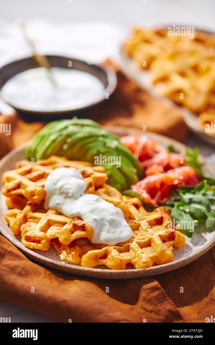 Hearty sweet potato or pumpkin waffles with avocado, salmon, arugula and sauce Stock Photo