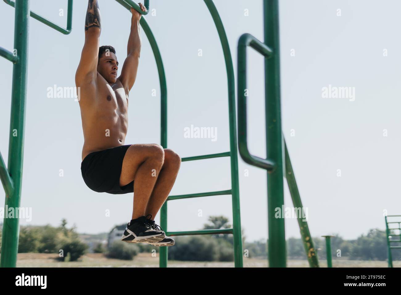 Active couple in park doing pull ups on horizontal metal bars ...